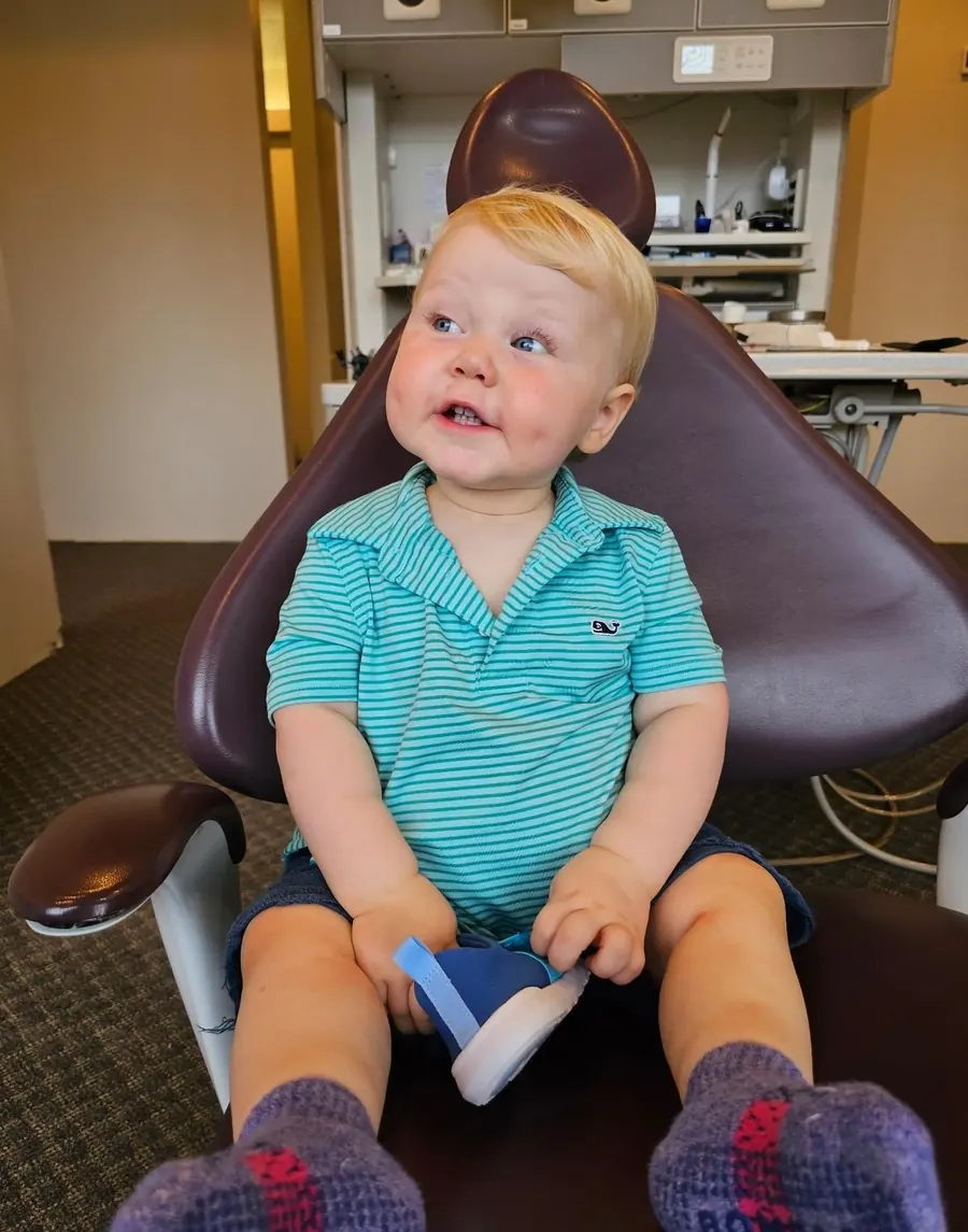 A toddler in a blue shirt sitting in a dental chair at Kerst & Caskey.